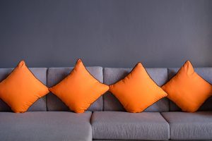 orange scatter cushion or backrest pillow on grey sofa.